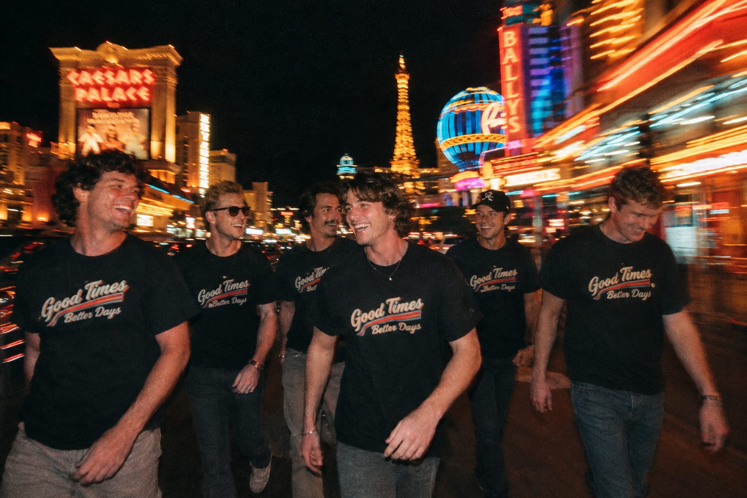 Groomsmen in matching black shirts on a neon-lit Las Vegas street at night